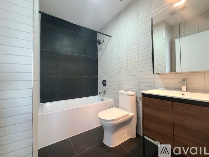A white toilet sits in a bathroom with a black tiled wall.