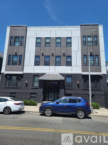 A blue car is parked in front of a modern building.