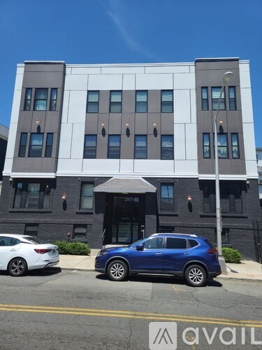 A blue car is parked in front of a modern building.