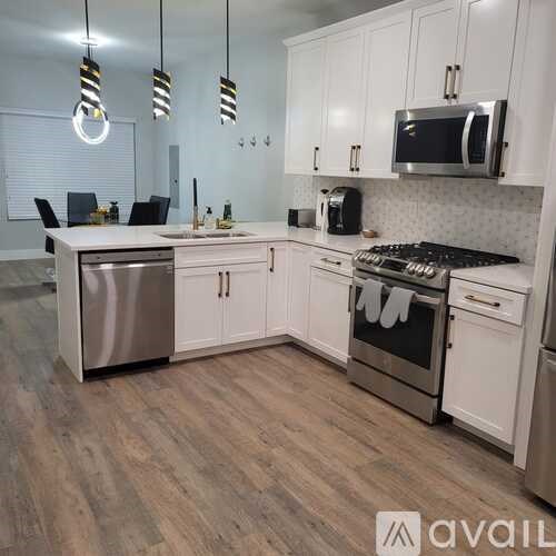 A modern kitchen with white cabinets and stainless steel appliances.
