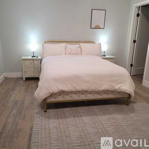 A bedroom with a large bed and two nightstands with lamps.