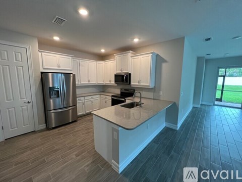 A kitchen with a refrigerator, microwave, and sink.