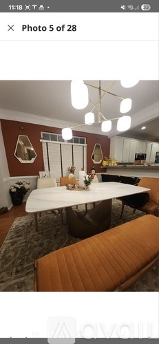 A modern dining room with a white table and orange bench.