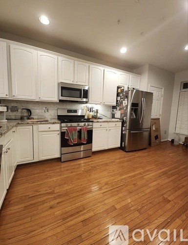 A kitchen with white cabinets and wooden floors.