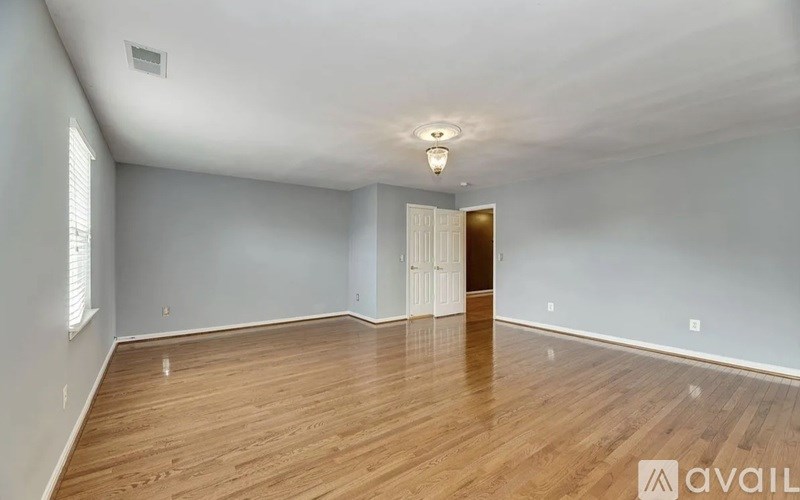 A spacious room with wooden flooring and a white door.