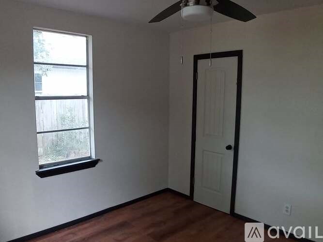 A room with a ceiling fan, a door, and a window.