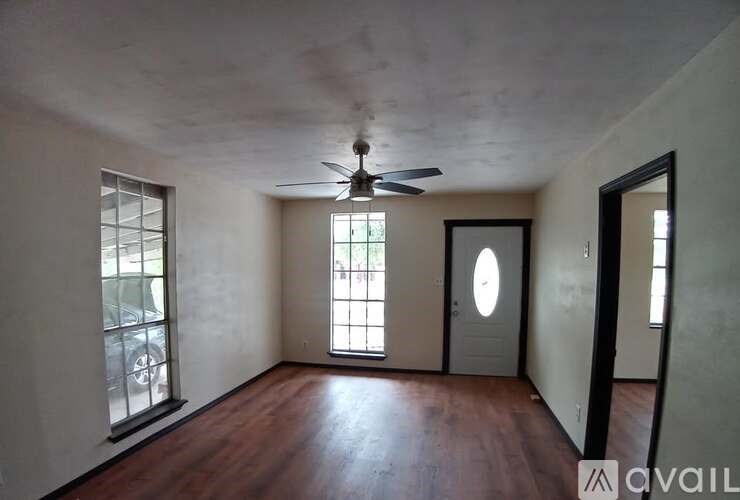 A room with a ceiling fan and a door with a round window.