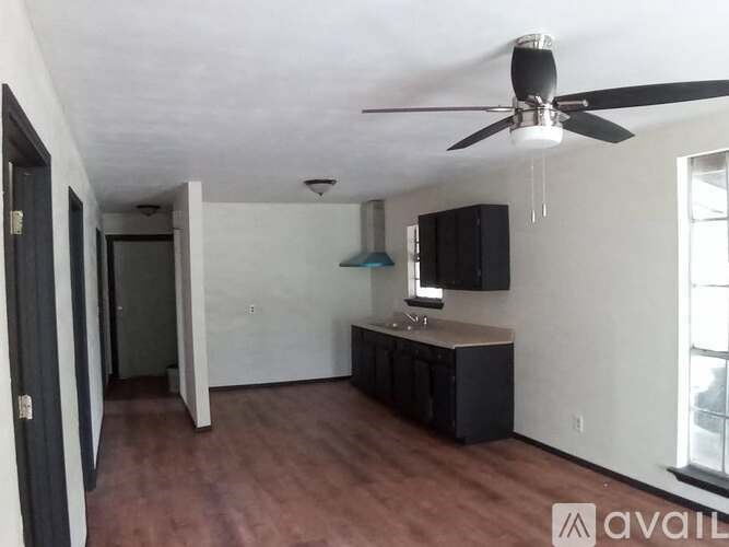 A room with a ceiling fan and a kitchenette.