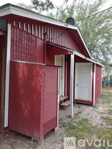 A red shed with a white door and a satellite dish on the roof.