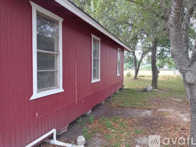 A red house with white windows and a tree in front.