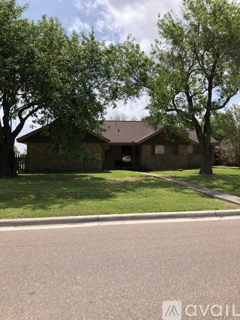 A house with a brown roof is surrounded by green trees.