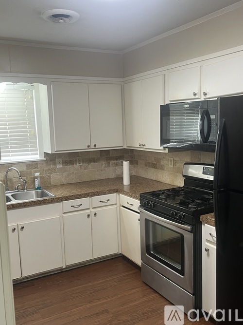 A kitchen with white cabinets and a black refrigerator.