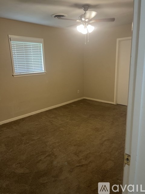 A room with a carpeted floor, a ceiling fan, and a window with blinds.