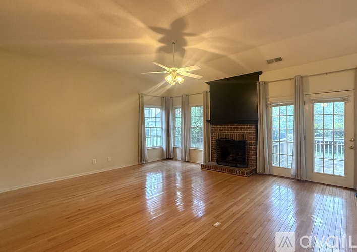 A room with a fireplace and a window with a floral curtain.