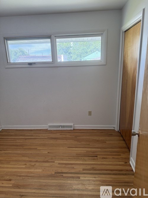 A room with wooden floors and a window overlooking a street.