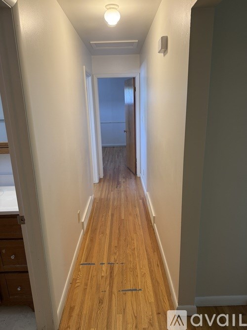 A long hallway with wood floors and white walls.