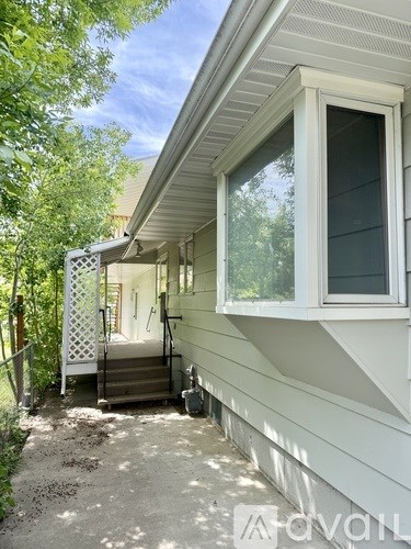 A white house with a porch and a trellis gate.