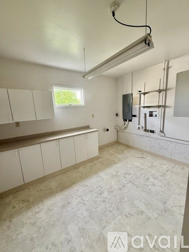 A room with white cabinets and a window is under construction.