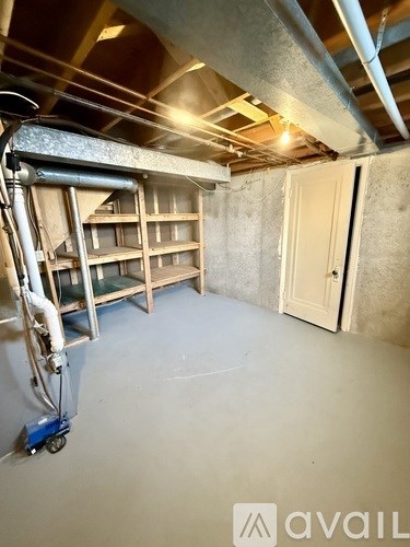A room with a metal pipe on the ceiling and a white door on the right side.