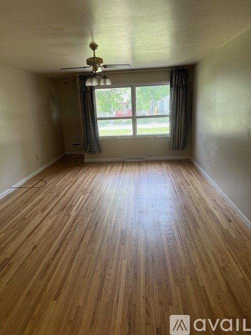 A room with wooden flooring and a ceiling fan.