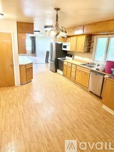 A kitchen with wooden floors and a black refrigerator.