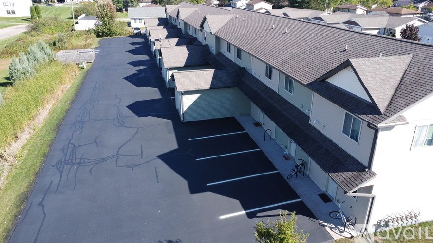 A parking lot in front of a building with a sign that says "AVAIL".