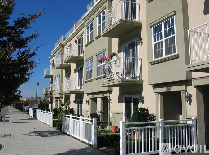 A row of apartment buildings with white fences in front.