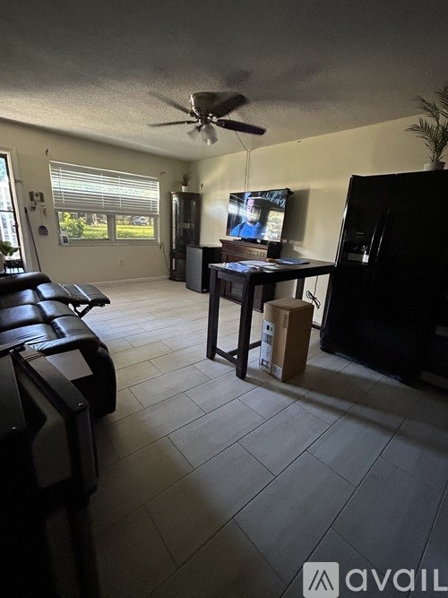 A living room with a black couch and a ceiling fan.