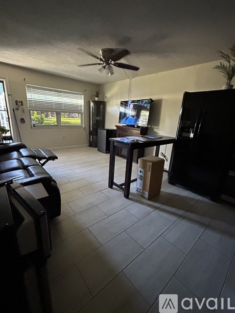 A living room with a black couch and a ceiling fan.