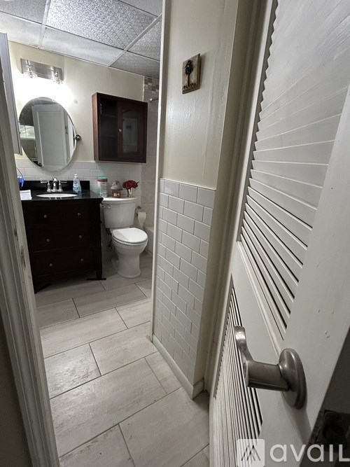 A bathroom with a toilet, sink, and mirror.