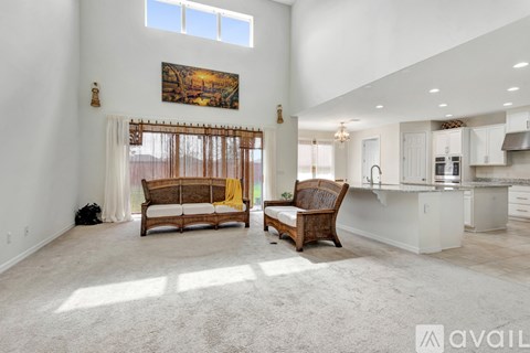 A living room with a couch and a chair in front of a kitchen.