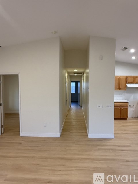 A spacious room with wooden flooring and large windows.
