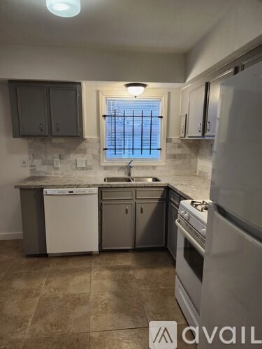 A kitchen with a white dishwasher and stove top oven.