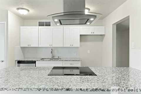 A kitchen with a granite countertop and white cabinets.