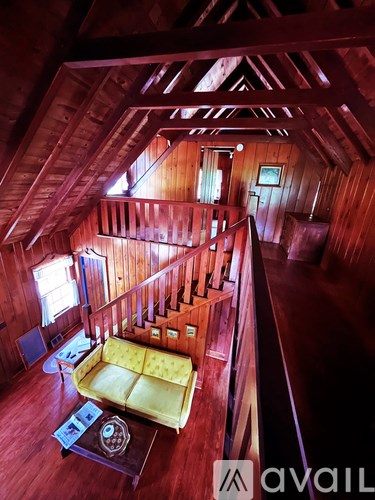 A living room with a yellow couch and a wooden floor.