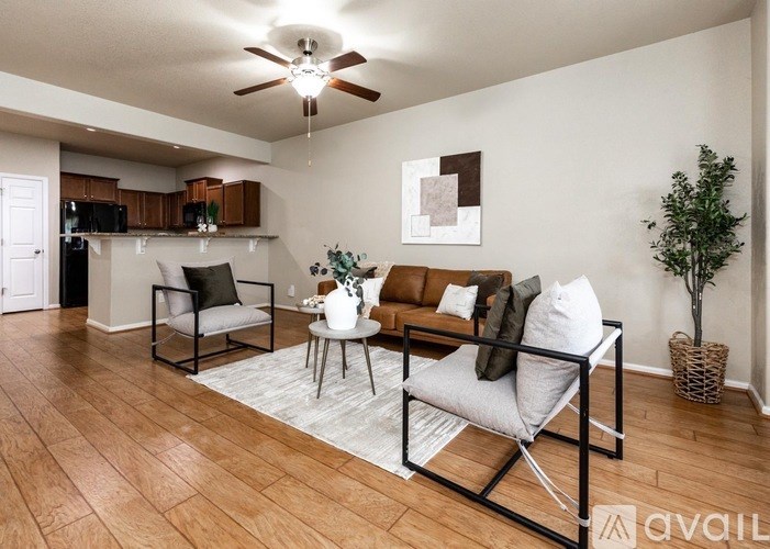 A living room with a brown sofa, a white chair, and a white coffee table.