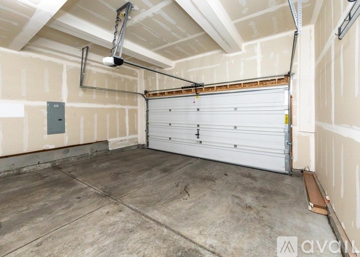 A spacious garage with a white roller shutter door and a ceiling fan.
