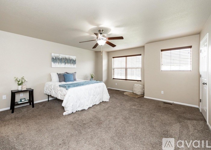 A bedroom with a bed, a ceiling fan, and a carpeted floor.