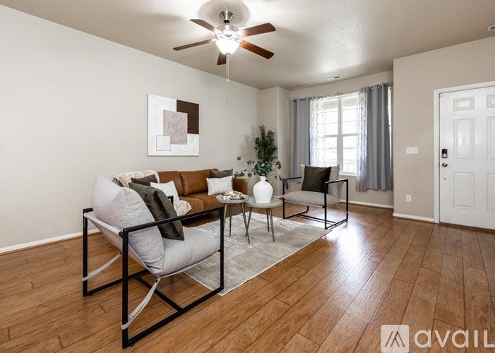 A living room with a white sofa, a grey armchair, and a small table with a vase on it.