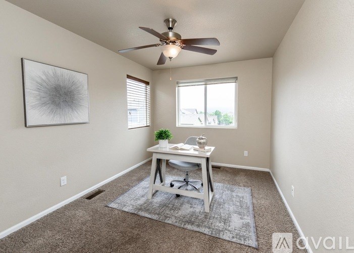 A room with a ceiling fan, a table with a plant, and a framed picture on the wall.