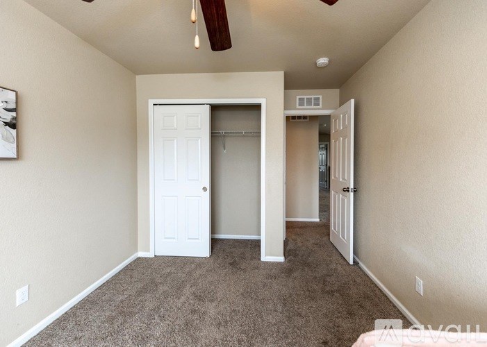 A room with a white door and a brown carpet.