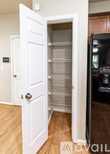 A white door is open to reveal a black refrigerator.