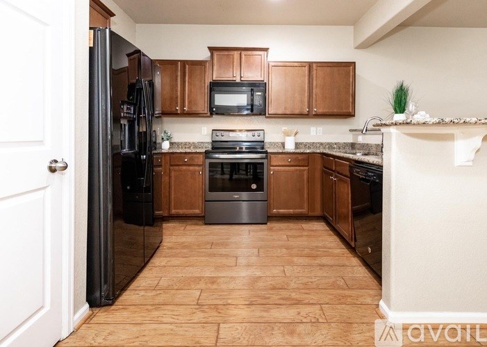A kitchen with wooden cabinets and a black refrigerator.