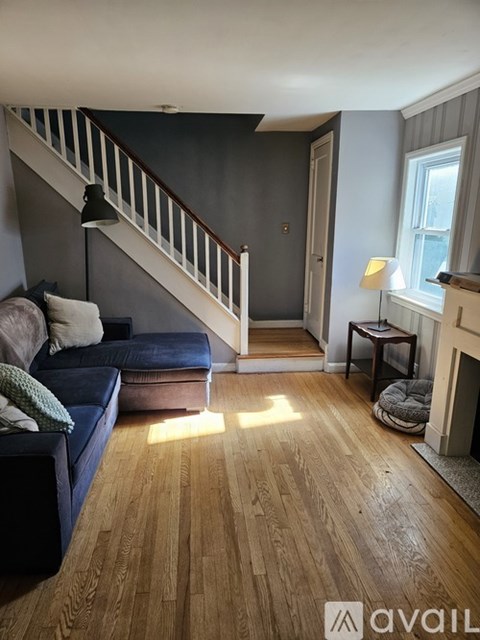A living room with a blue couch and a wooden floor.