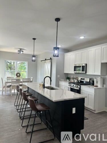 A kitchen with a black island and white cabinets.