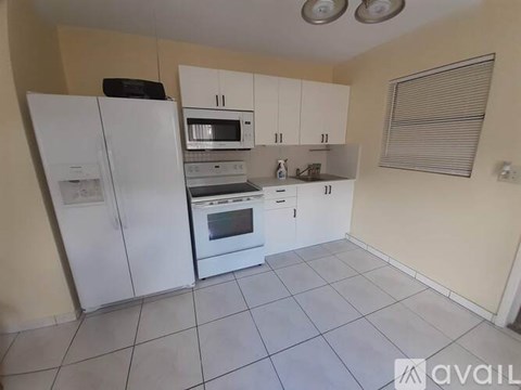 A kitchen with white appliances and cabinets is available for rent.