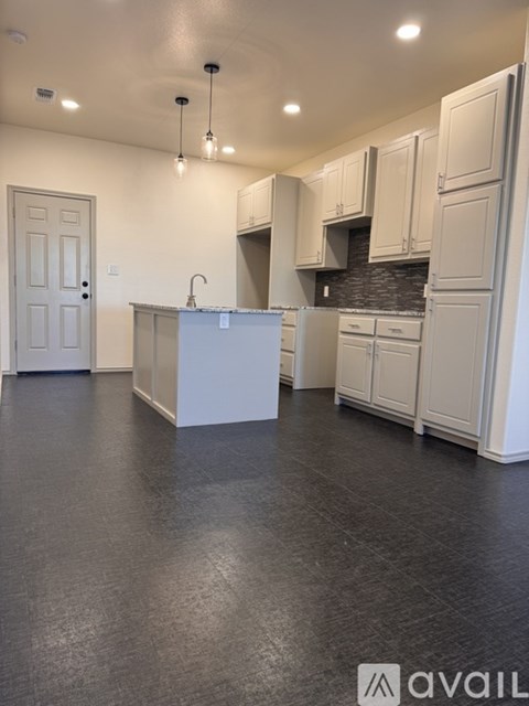 A kitchen with white cabinets and a grey floor.