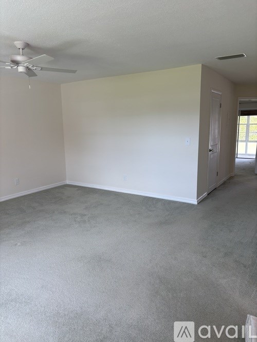 A room with a ceiling fan and a door leading to another room.