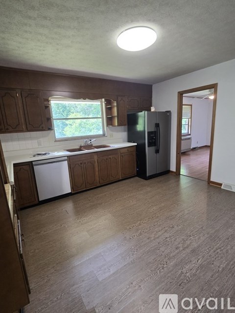 A kitchen with wooden cabinets and a black refrigerator.