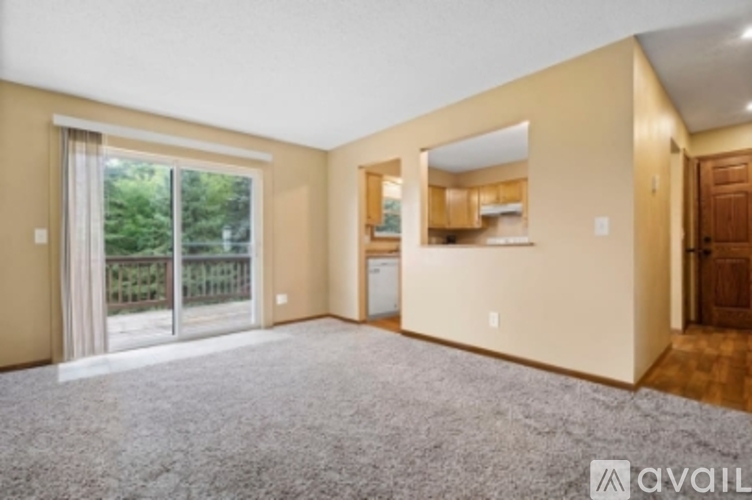 A spacious living room with a sliding glass door leading to a balcony.